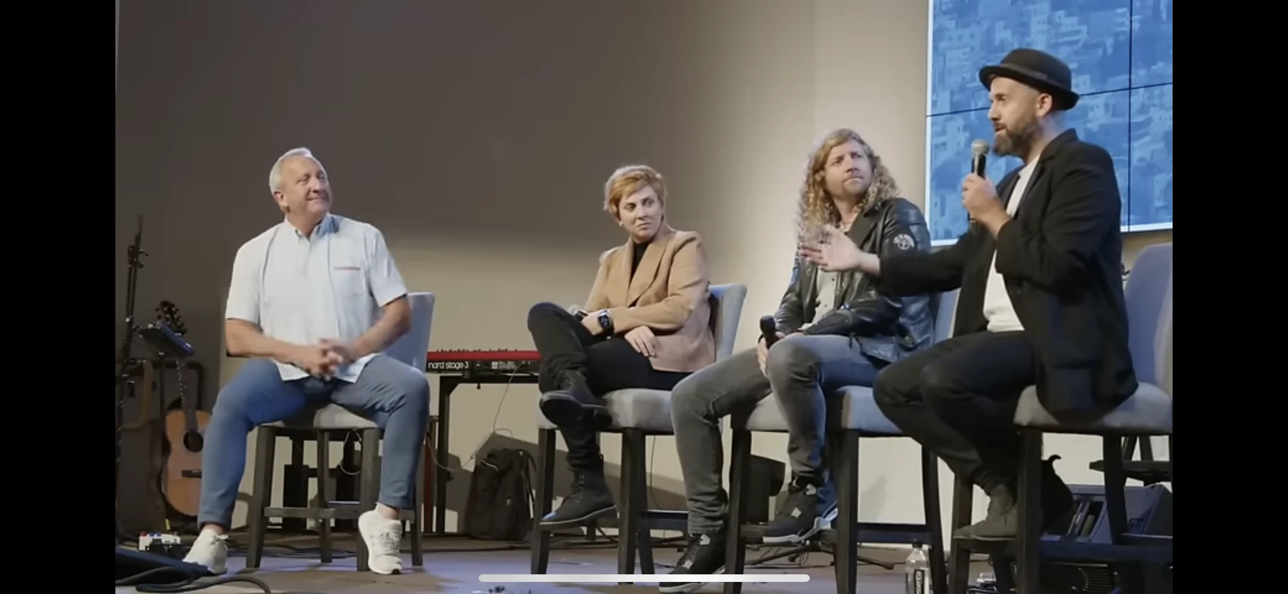 Yair sharing a conversation with fellow musicians and a host, seated together on stage